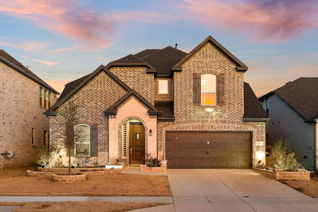 french provincial home featuring driveway, roof with shingles, and brick siding