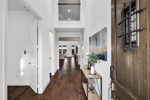 foyer entrance with a high ceiling, baseboards, and dark wood-type flooring