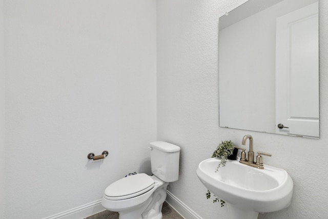 bathroom featuring a sink, toilet, and baseboards