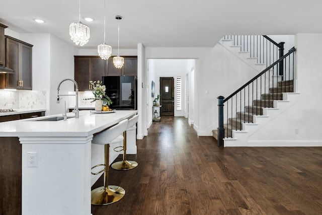 kitchen with light countertops, dark brown cabinets, a sink, and pendant lighting