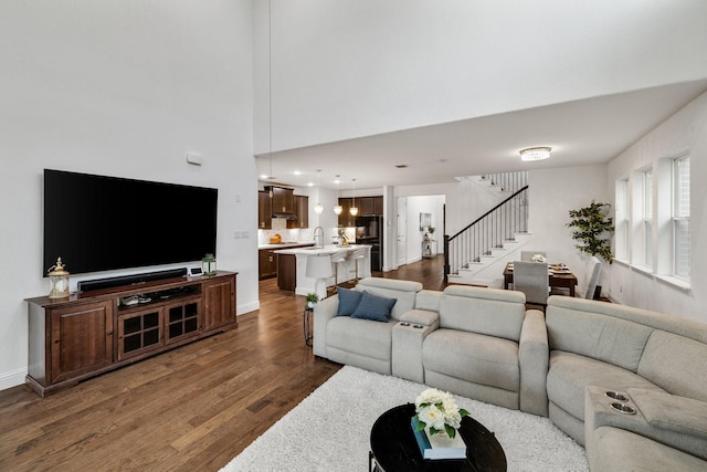 living room with dark wood-type flooring, recessed lighting, baseboards, and stairs