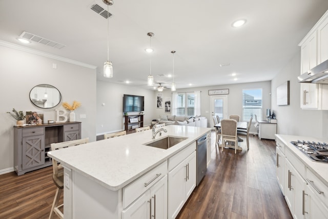 kitchen with decorative light fixtures, a center island with sink, visible vents, appliances with stainless steel finishes, and a sink