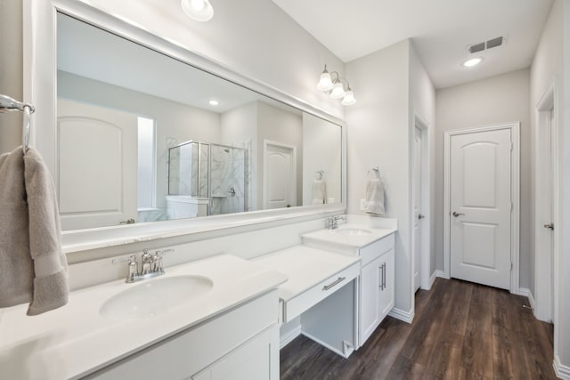 full bath featuring wood finished floors, a stall shower, a sink, and visible vents