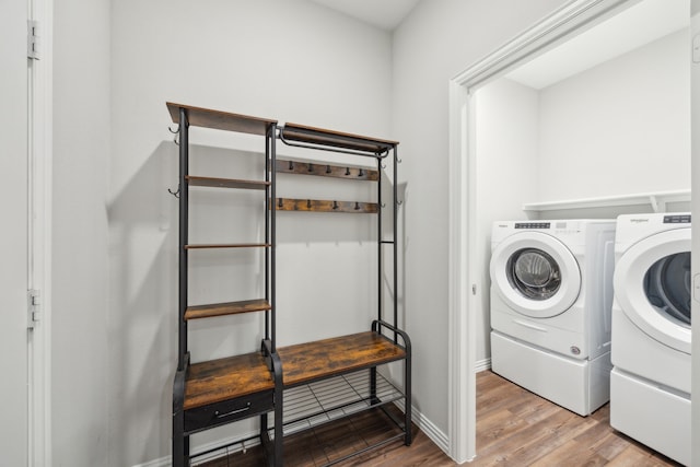 clothes washing area featuring laundry area, washing machine and dryer, baseboards, and wood finished floors