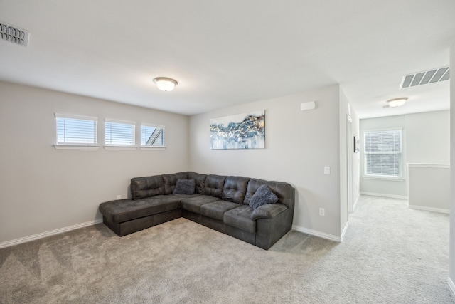 living room featuring baseboards, visible vents, and light colored carpet