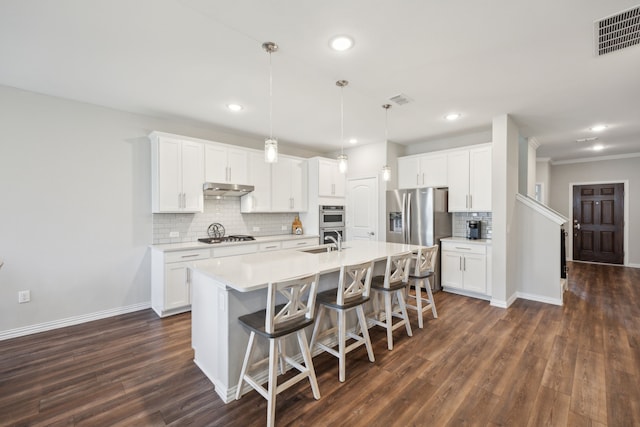 kitchen featuring visible vents, white cabinets, light countertops, under cabinet range hood, and pendant lighting