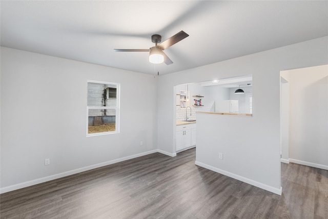 unfurnished room with sink, plenty of natural light, dark hardwood / wood-style floors, and ceiling fan