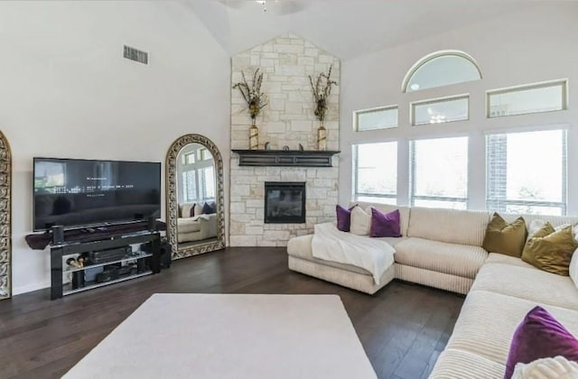 living area featuring high vaulted ceiling, dark wood-type flooring, a fireplace, and visible vents