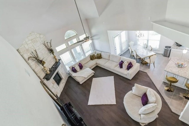 living room with ceiling fan with notable chandelier, high vaulted ceiling, wood finished floors, and a healthy amount of sunlight