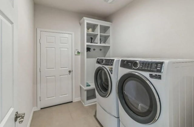 laundry room featuring laundry area, light tile patterned flooring, washing machine and clothes dryer, and baseboards