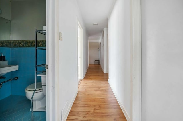 hallway with tile walls and light hardwood / wood-style flooring