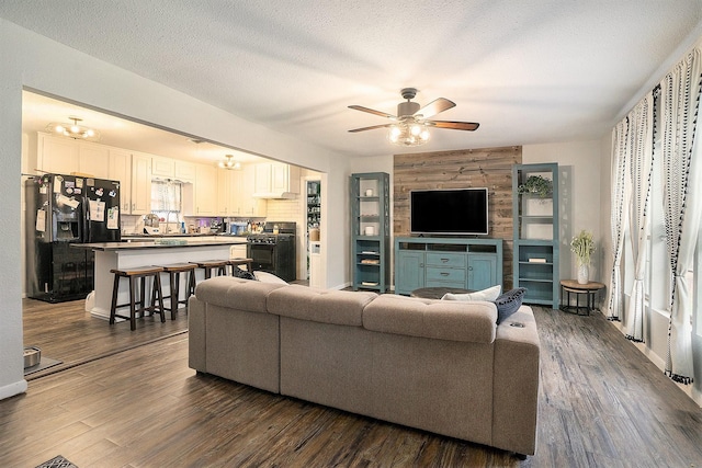 living room with ceiling fan, dark hardwood / wood-style floors, and a textured ceiling