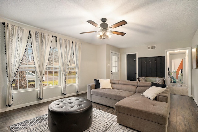 living room with ceiling fan, plenty of natural light, a textured ceiling, and dark hardwood / wood-style flooring