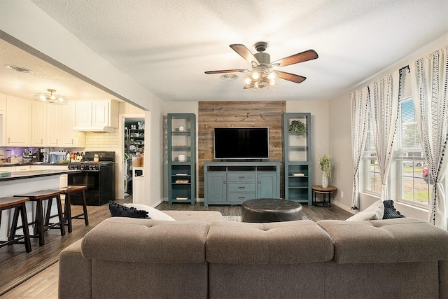 living room with ceiling fan, light hardwood / wood-style floors, and a textured ceiling