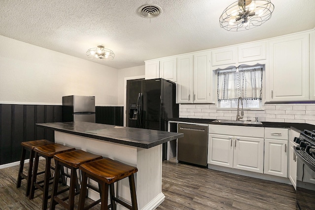 kitchen featuring sink, dark wood-type flooring, black appliances, white cabinets, and a kitchen bar