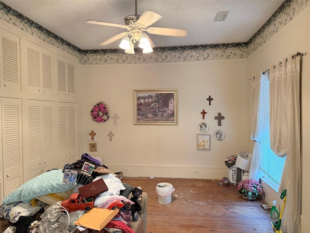 unfurnished bedroom with wood finished floors, a ceiling fan, baseboards, a textured ceiling, and a closet