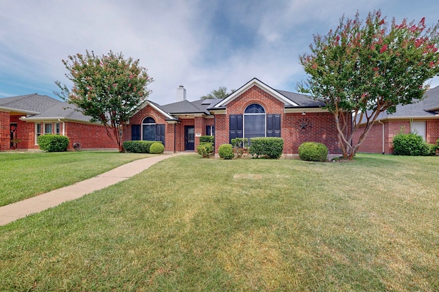 single story home with brick siding, a chimney, and a front yard