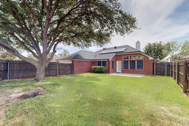 1720 Willow Crk, Mesquite, TX 75181 - back of house with roof mounted solar panels, a fenced backyard, a lawn, brick siding, and a chimney