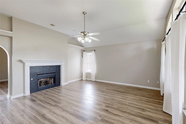 unfurnished living room featuring ceiling fan, a fireplace, vaulted ceiling, and light hardwood / wood-style flooring