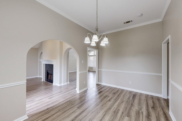 unfurnished dining area with ornamental molding, hardwood / wood-style flooring, and a notable chandelier