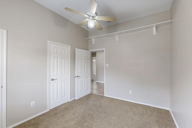 unfurnished bedroom featuring baseboards, carpet floors, attic access, and a ceiling fan