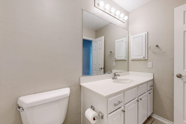 bathroom featuring toilet, vanity, and baseboards