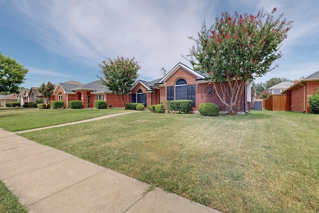 view of front of house with a front yard, fence, brick siding, and a chimney