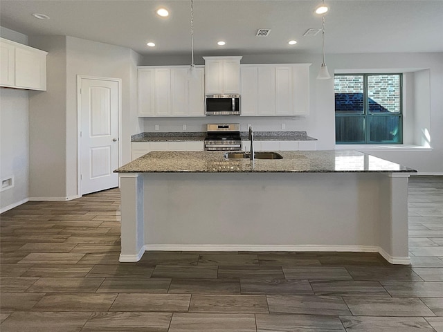 kitchen with appliances with stainless steel finishes, sink, a center island with sink, and white cabinets