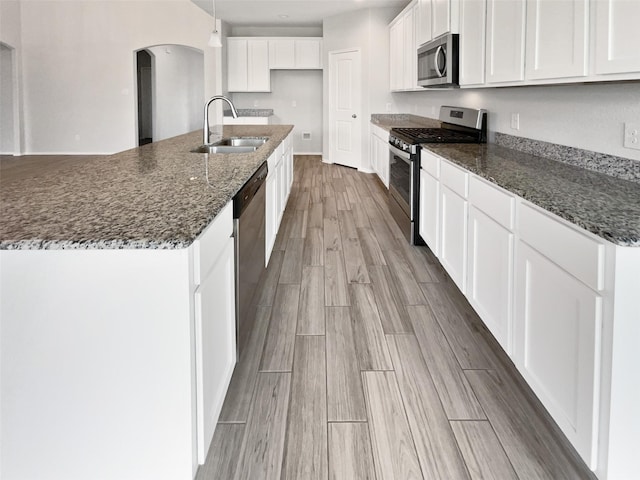 6416 Texas Cowboy Dr, Fort Worth, TX 76123 - kitchen with stainless steel appliances, a sink, arched walkways, light wood finished floors, and white cabinetry