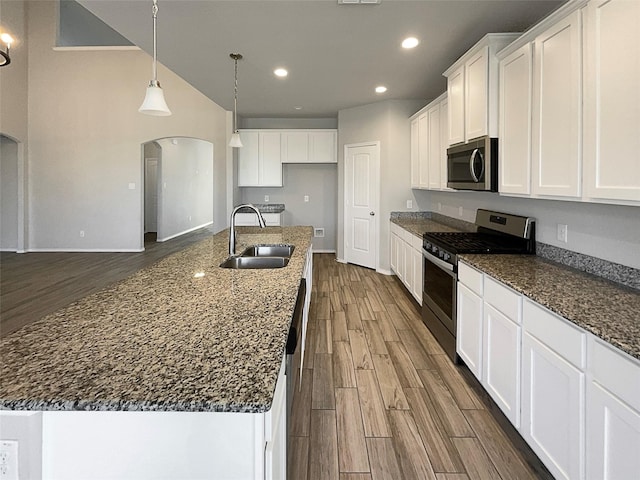 kitchen with sink, decorative light fixtures, a center island with sink, stainless steel appliances, and white cabinets