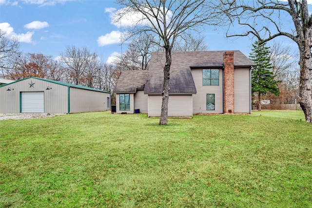 rear view of property featuring a garage, an outbuilding, and a lawn