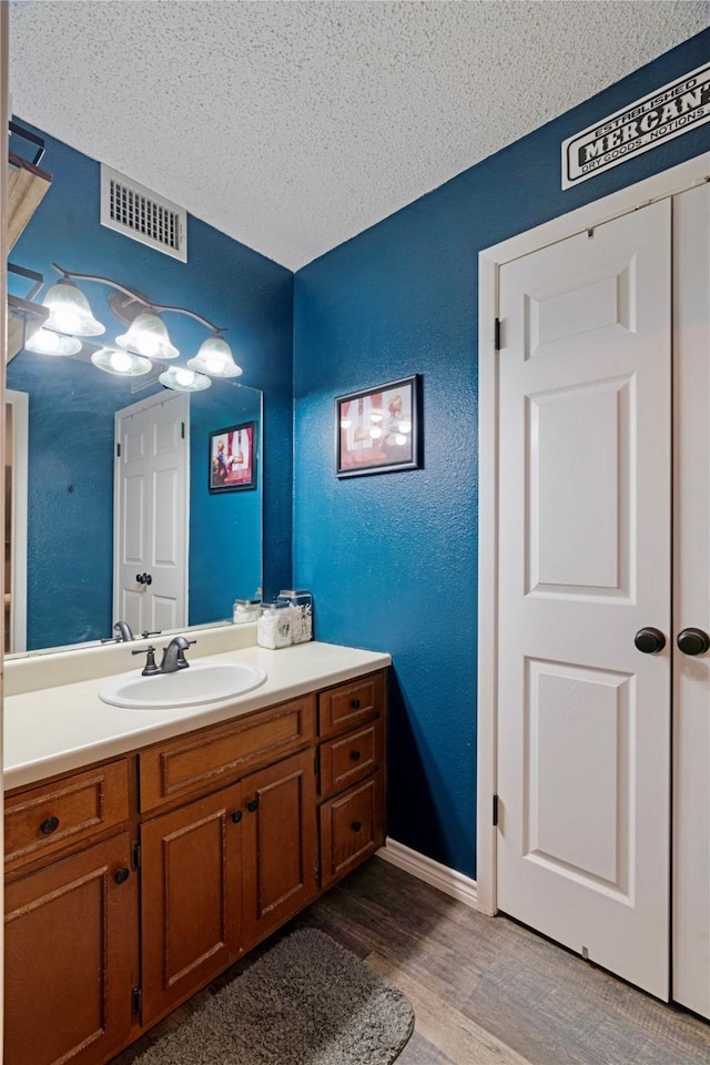 bathroom featuring hardwood / wood-style flooring, vanity, and a textured ceiling