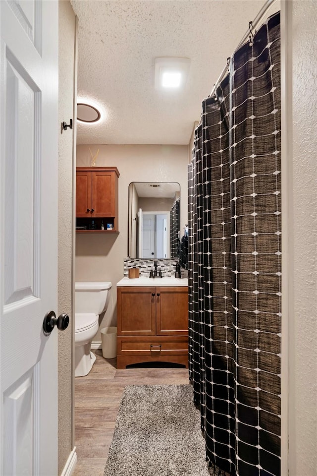 bathroom featuring hardwood / wood-style flooring, vanity, toilet, and a textured ceiling