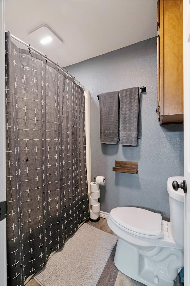 bathroom featuring a shower with curtain, wood-type flooring, and toilet