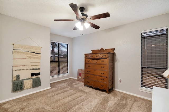 bedroom with ceiling fan, light colored carpet, and a textured ceiling