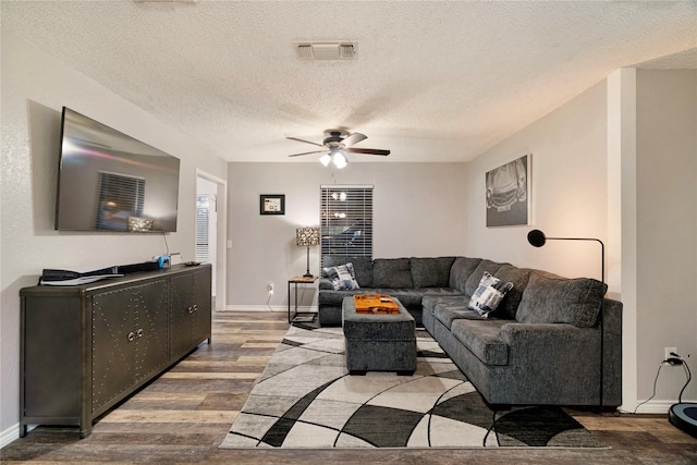 living room featuring ceiling fan, wood-type flooring, and a textured ceiling