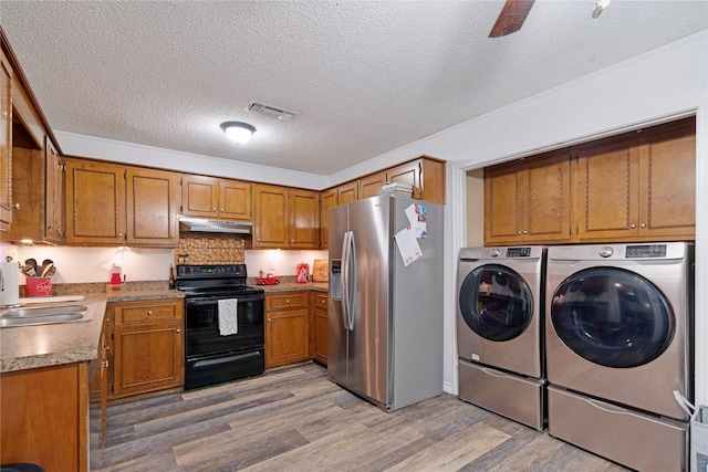 kitchen featuring sink, stainless steel fridge, black range with electric stovetop, light wood-type flooring, and washing machine and dryer