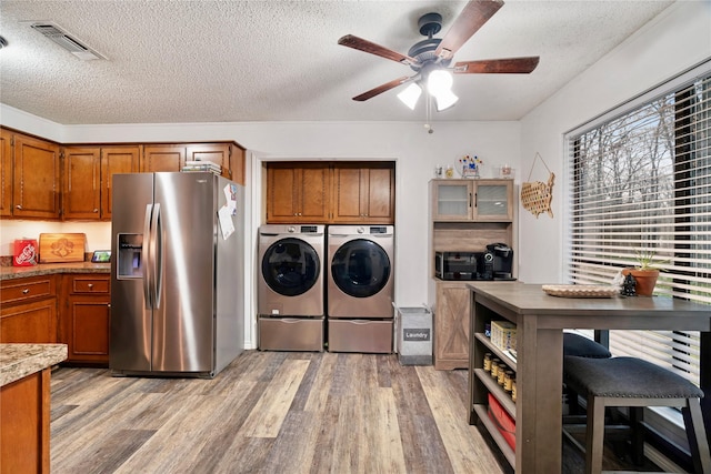 laundry room featuring cabinets, washer and dryer, a textured ceiling, and light hardwood / wood-style flooring