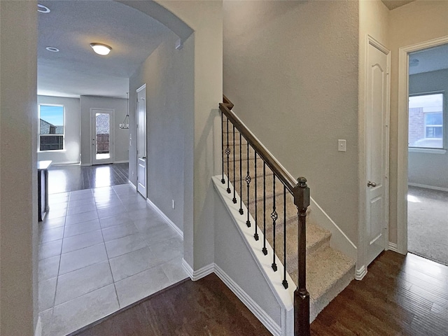 stairway with plenty of natural light and wood-type flooring