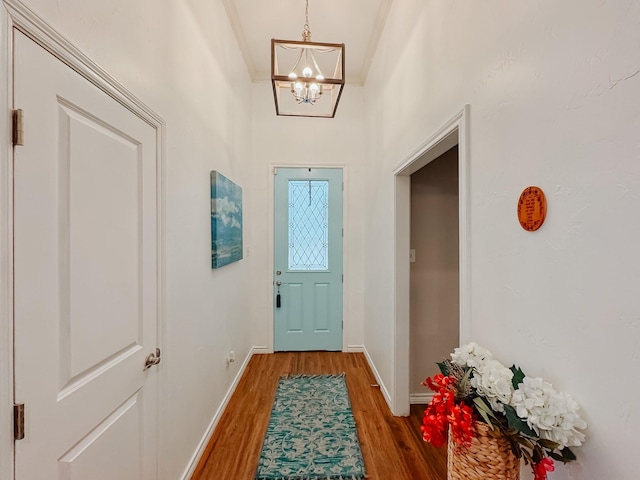 doorway featuring wood-type flooring, crown molding, and an inviting chandelier