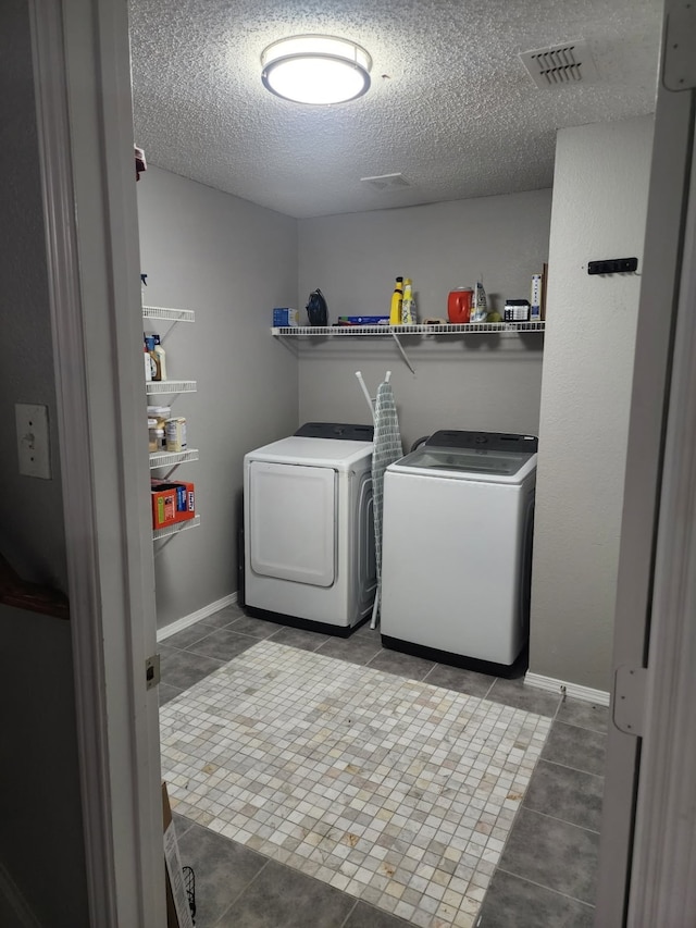 clothes washing area featuring light tile patterned flooring, separate washer and dryer, and a textured ceiling