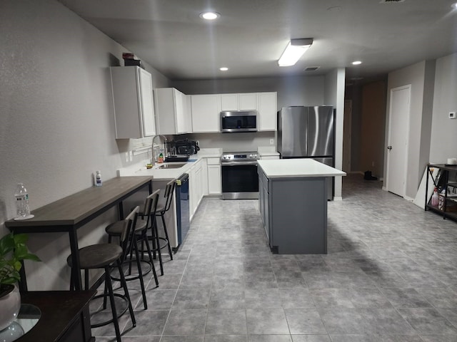 kitchen featuring stainless steel appliances, sink, a kitchen island, and white cabinets