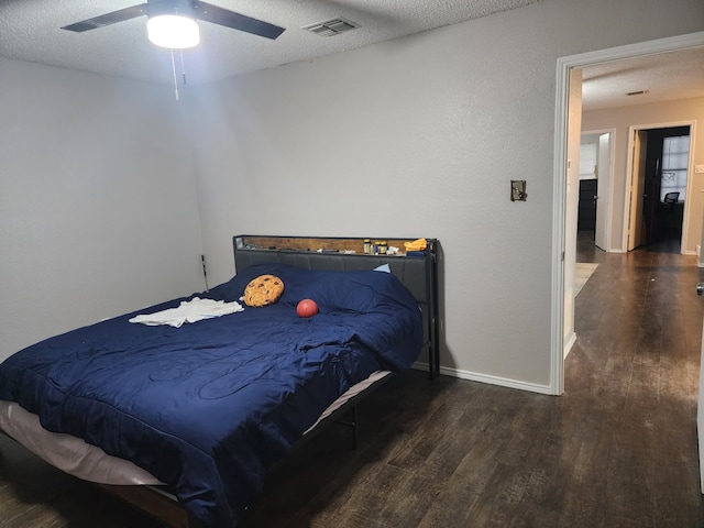 bedroom featuring ceiling fan, dark hardwood / wood-style floors, and a textured ceiling