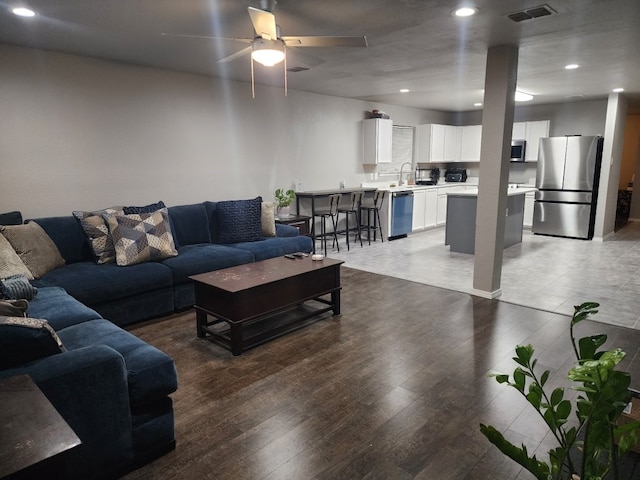 living room with hardwood / wood-style flooring, ceiling fan, and sink