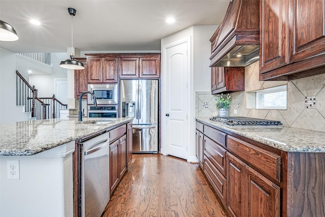 kitchen featuring stainless steel appliances, a sink, custom range hood, dark wood-style floors, and pendant lighting