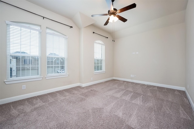 empty room featuring vaulted ceiling, carpet flooring, ceiling fan, and baseboards