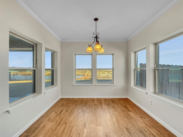 unfurnished dining area featuring ornamental molding, a chandelier, and light hardwood / wood-style floors