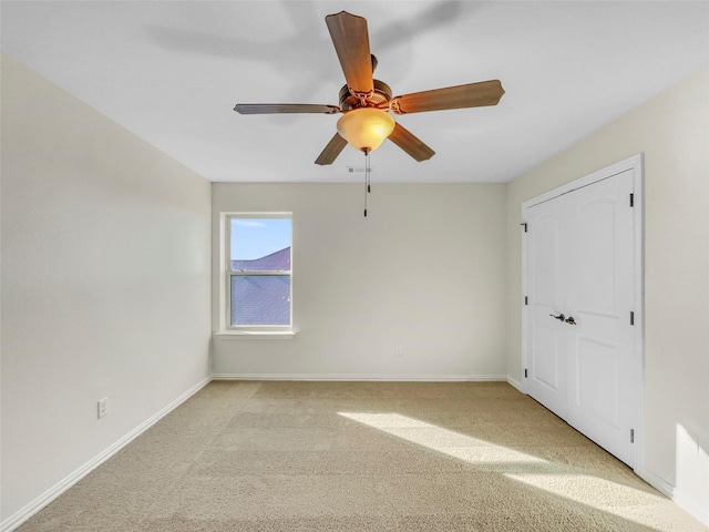 empty room featuring ceiling fan and light colored carpet