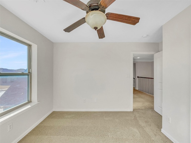 spare room with ceiling fan, light colored carpet, and a healthy amount of sunlight