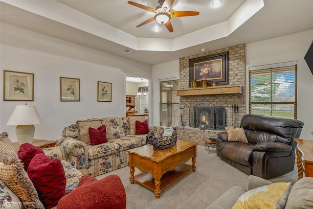 carpeted living room featuring a fireplace, a raised ceiling, and ceiling fan